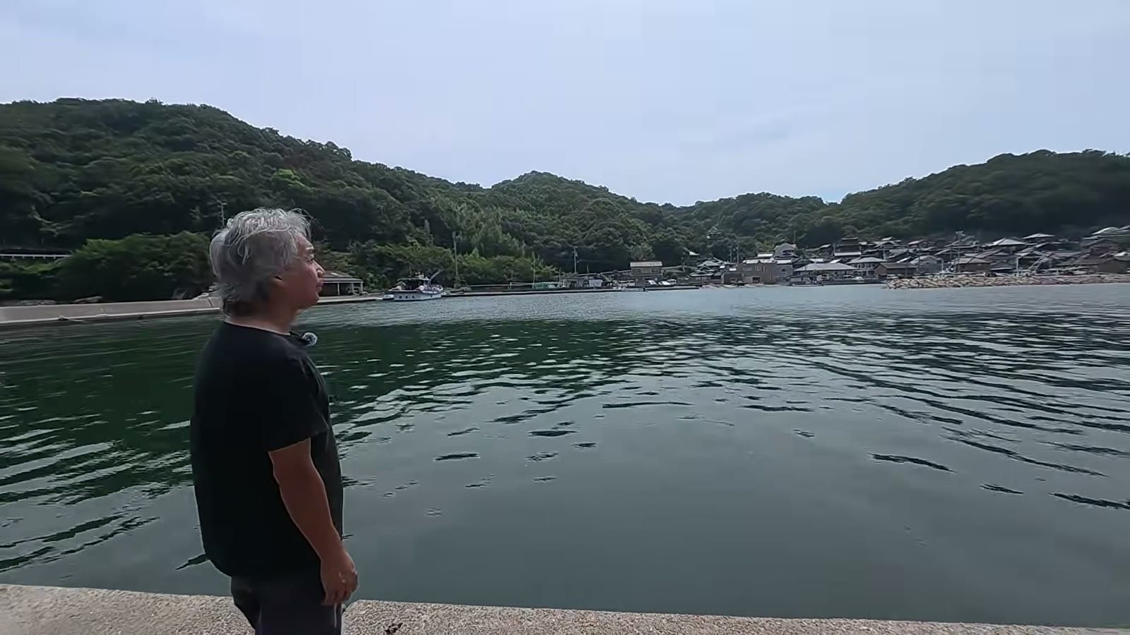 岸壁に立ち、海の向こうの瀬居島の町並みを眺める宮前